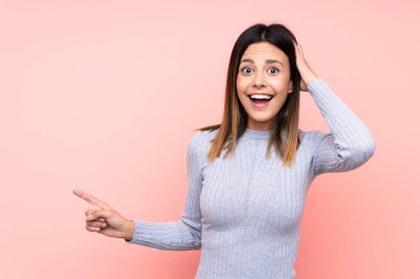 Soyutlanmış pembe arka plandaki kadın şaşırdı ve parmağını yana çevirdi.