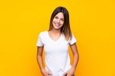 Sarı arka planda yaşayan genç bir kadın gülüyor.
