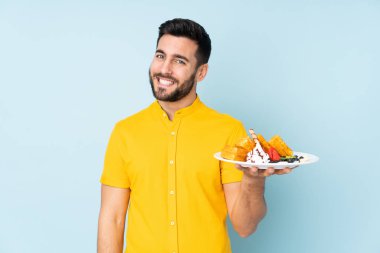 Beyaz adam mavi arka planda gözleme tutuyor.