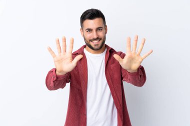 Sakallı, kadife ceket giyen genç yakışıklı bir adam izole edilmiş beyaz arka planda parmaklarıyla ona kadar sayıyor.