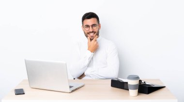 İş yerinde gözlüklü ve gülümseyen genç bir işadamı.