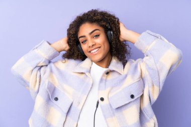 Genç Afrikalı Amerikalı kadın, mor arka planda izole edilmiş müzik dinliyor.