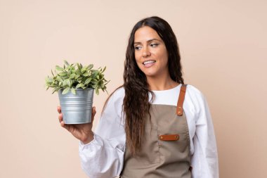 Genç bir kadın elinde mutlu bir ifadeyle bir bitki tutuyor.