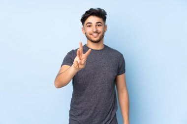 Soyutlanmış geçmişi olan yakışıklı Arap bir adam mutlu ve parmaklarıyla üçe kadar sayıyor.