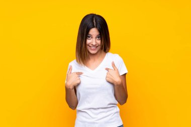 Yüzünde sürpriz ifade olan, izole edilmiş sarı arka planda genç bir kadın.