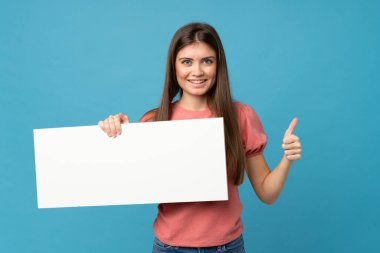 İzole edilmiş mavi arka plan üzerinde genç bir kadın bir konsept eklemek için boş beyaz bir levha tutuyor.