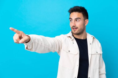 Soyutlanmış mavi arka planı olan yakışıklı bir genç.