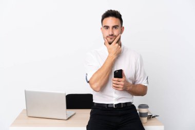 İş yerinde cep telefonu olan genç bir iş adamı bir fikir düşünüyor.