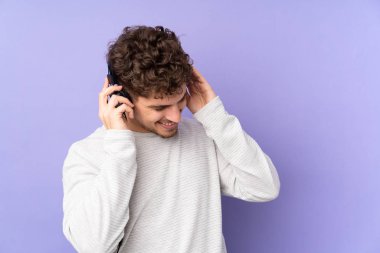 Mor arka planda izole edilmiş beyaz adam müzik dinliyor.