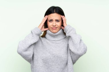 İzole edilmiş yeşil arka planda kazak giyen bir kadın mutsuz ve hayal kırıklığına uğramış. Olumsuz yüz ifadesi