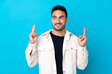 Soyutlanmış mavi arka planda genç yakışıklı bir adam.