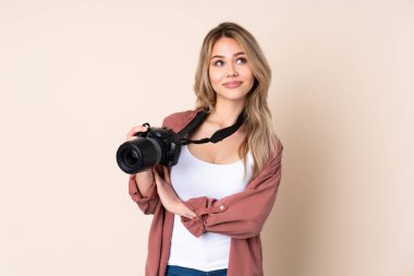 Genç fotoğrafçı kız tebessümle yukarı bakıyor.