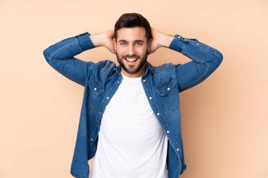 Beyaz tenli yakışıklı adam bej arka planda izole edilmiş gülüyor.