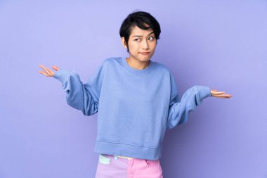 Mor arka planda kısa saçlı genç Vietnamlı kadın ellerini kaldırırken şüpheleri var.