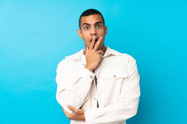 Genç Afrikalı Amerikalı bir adam mavi arka planda, sağa bakarken şaşırmış ve şok olmuştu.