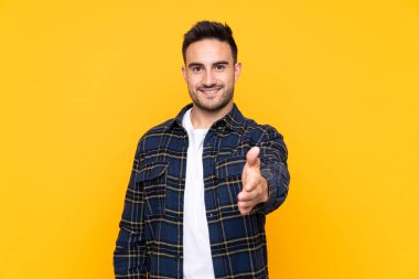 İyi bir anlaşma dan sonra izole sarı arka plan handshaking üzerinde Genç yakışıklı adam