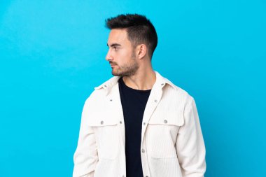 Soyutlanmış mavi arka planda genç yakışıklı bir adam.