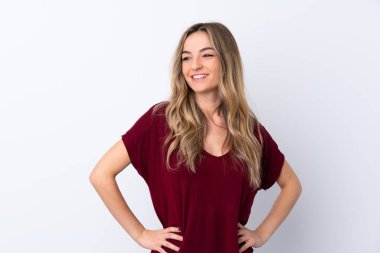 İzole edilmiş beyaz arka planda genç bir kadın kolları kalçasında ve gülümsüyor.