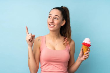 Kornet dondurması ile izole edilmiş mavi arka planı olan esmer bir kadın çözümü bulmak için parmağını kaldırıyor.