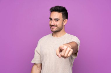 Mor arka planda kalan yakışıklı genç adam kendine güvenen bir ifadeyle seni işaret ediyor.