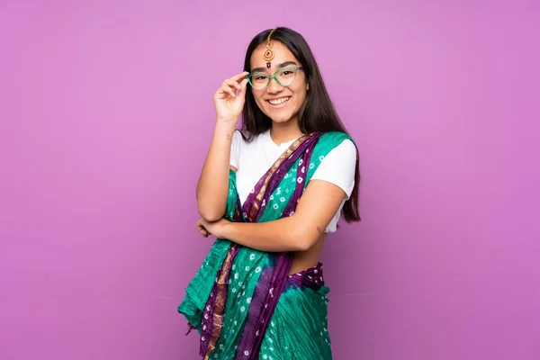 Young Indian woman with sari over isolated background with glasses and happy