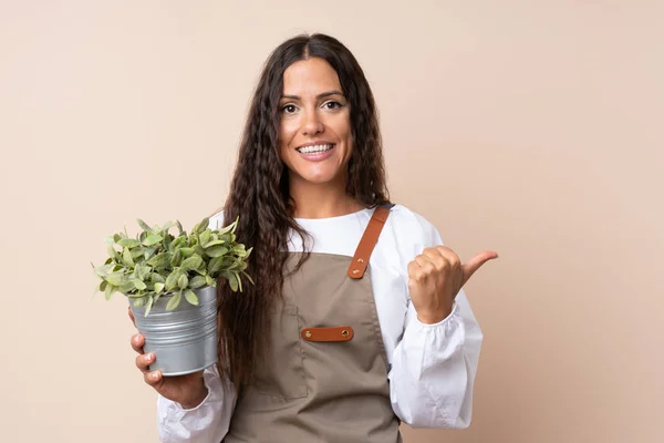 Mujer Joven Sosteniendo Una Planta Apuntando Hacia Lado Para Presentar — Foto de Stock