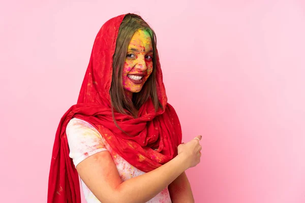 若いですインド人女性とともにカラフルなホリパウダーオン彼女の顔絶縁上のピンクの背景指摘 — ストック写真