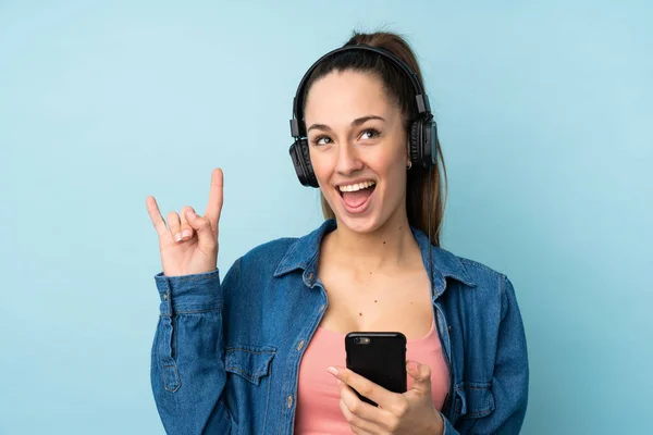 Giovane Donna Bruna Sfondo Blu Isolato Ascoltare Musica Con Cellulare — Foto Stock