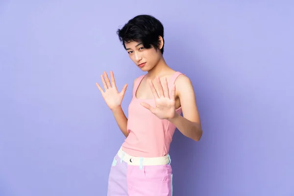 若いですベトナム人女性とともに短い髪上隔離された紫色の背景神経伸張手へ前 — ストック写真