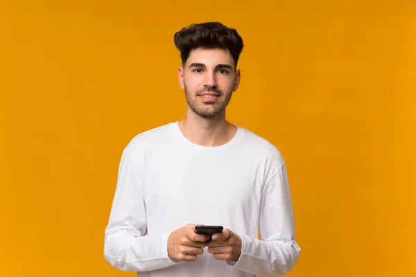 Fiatal Férfi Elszigetelt Narancs Háttér Küld Egy Üzenetet Mobil — Stock Fotó
