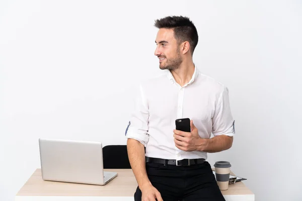 Young business man with a mobile phone in a workplace looking to the side