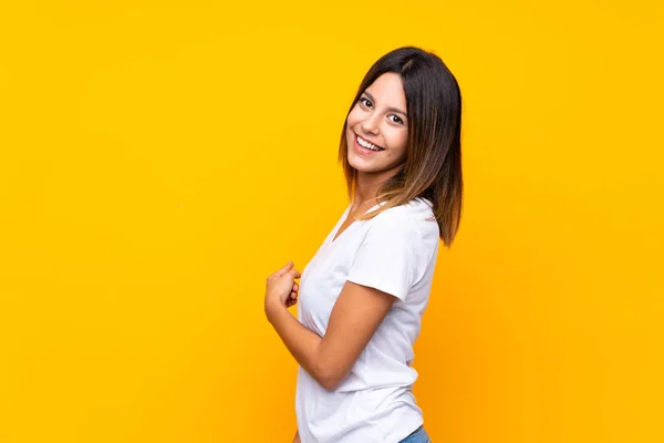 Mujer Joven Sobre Fondo Amarillo Aislado Apuntando Hacia Atrás —  Fotos de Stock