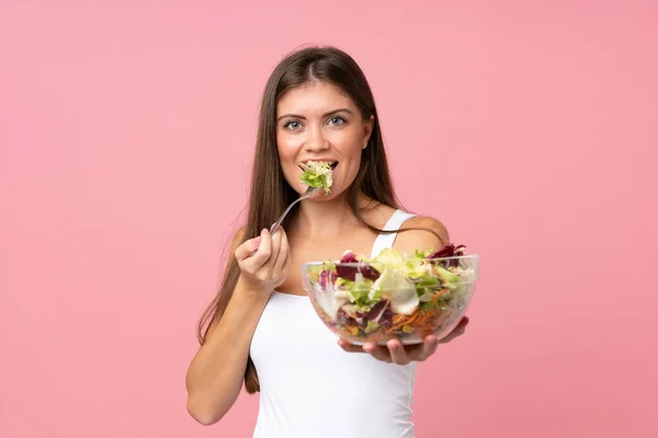 Young woman with salad over isolated pink wall