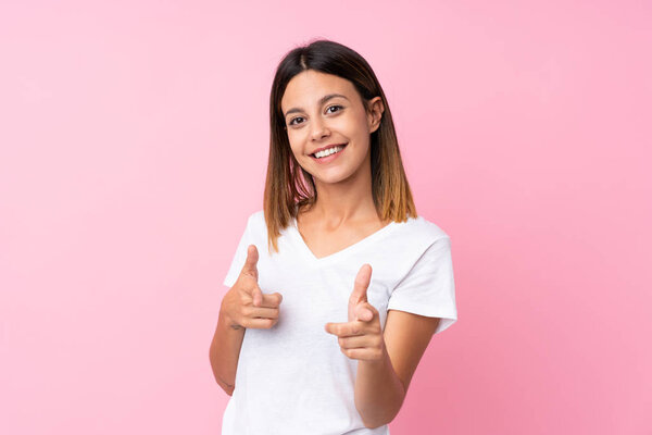 Young woman over isolated pink background pointing to the front and smiling