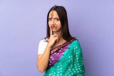 Mor arka planda izole edilmiş genç Hintli kadın yukarı bakarken şüphe duyuyor.