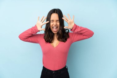 Mavi arka planda izole edilmiş genç melez kadın parmaklarıyla ona kadar sayıyor.