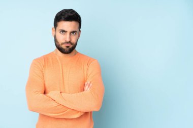 Beyaz, yakışıklı bir adam, mavi arka plan yüzünden üzgün.