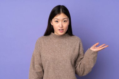 Mor arka planda izole edilmiş genç Asyalı kadın şüpheli hareketler yapıyor.