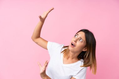 Soyutlanmış, pembe arka plan gergin ve korkmuş genç bir kadın.