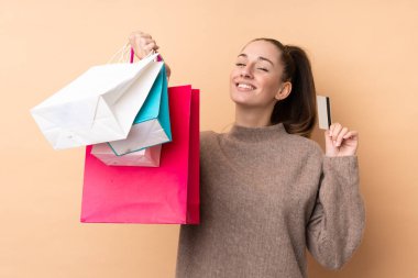 Genç esmer bir kadın, izole edilmiş bir geçmişi var. Elinde alışveriş çantaları ve kredi kartı var.