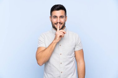 Sakallı, mavi arka planda genç ve yakışıklı bir adam sessizlik hareketi yapıyor.
