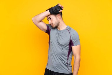 İzole edilmiş sarı duvarda yorgun yüzlü bir sporcu.