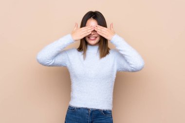 İzole edilmiş arka planda genç bir kadın elleriyle gözlerini kapatıyor.