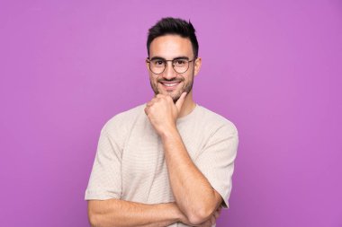 Gözlüklü, gülümseyen, soyutlanmış, mor bir geçmişi olan yakışıklı bir adam.