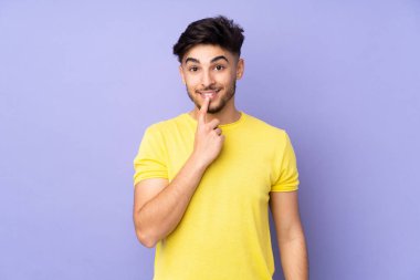 Münzevi bir geçmişi olan Arap yakışıklı bir adam sessizlik işareti gösteriyor. Parmağını ağzına sokuyor.