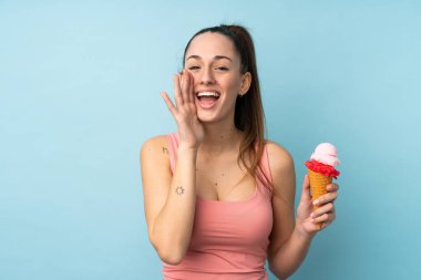 Kornet dondurmalı genç esmer kadın izole edilmiş mavi arka planda ağzı açık bağırıyor.