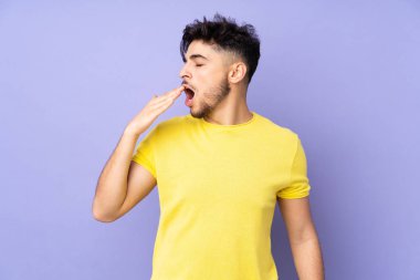 Arap yakışıklı adam izole edilmiş arka planda esniyor ve ağzını eliyle kapatıyor.