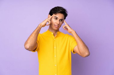 İzole edilmiş mor arka planı olan, kuşkulu ve düşünceli bir adam.