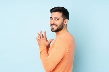 Caucasian handsome man scheming something over isolated blue background clipart