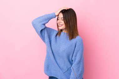 Young woman with blue sweater over isolated pink background laughing